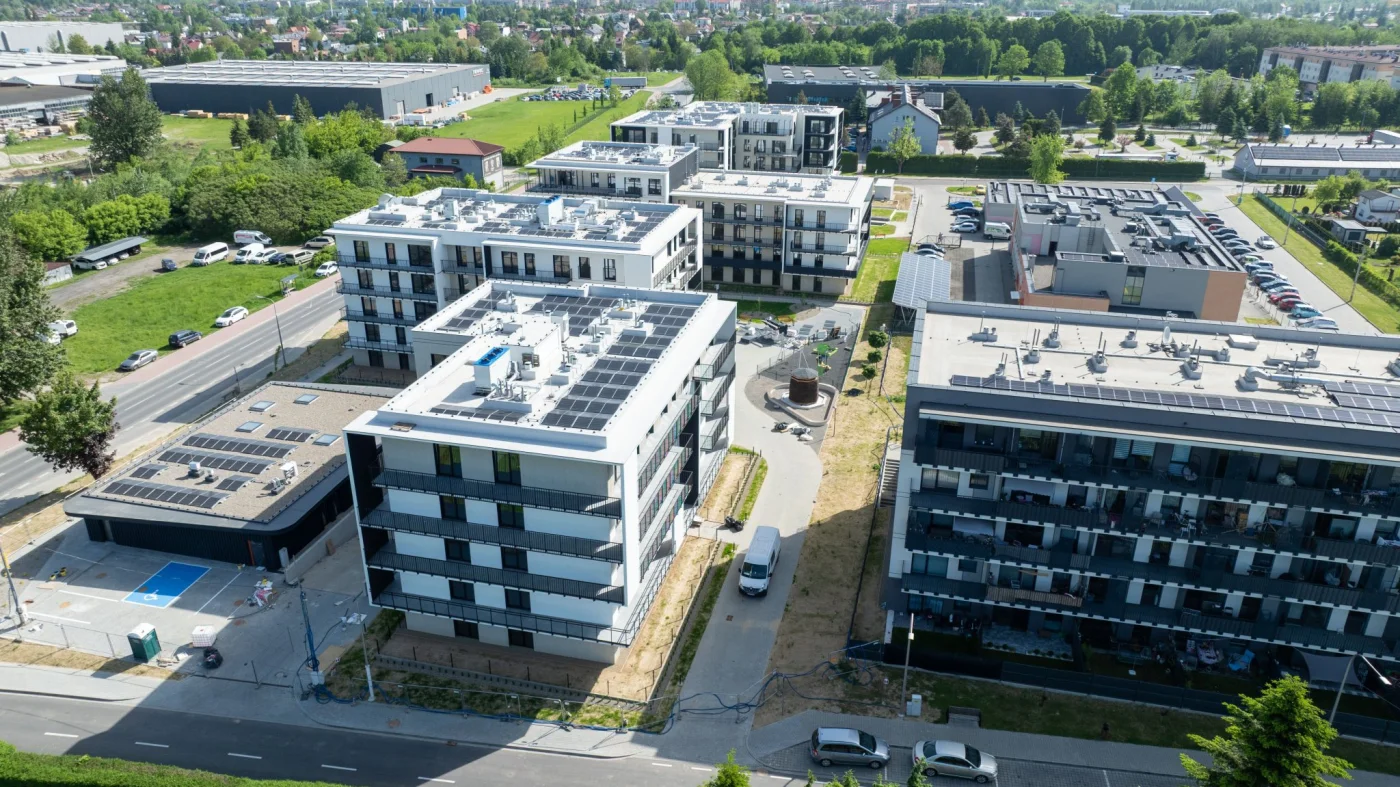 Budowa nowych bloków mieszkalnych w ramach inwestycji STBS przy ul. 29 listopada. Widoczne są nowoczesne budynki o białych elewacjach i czarnych balkonach, gotowe do zamieszkania.