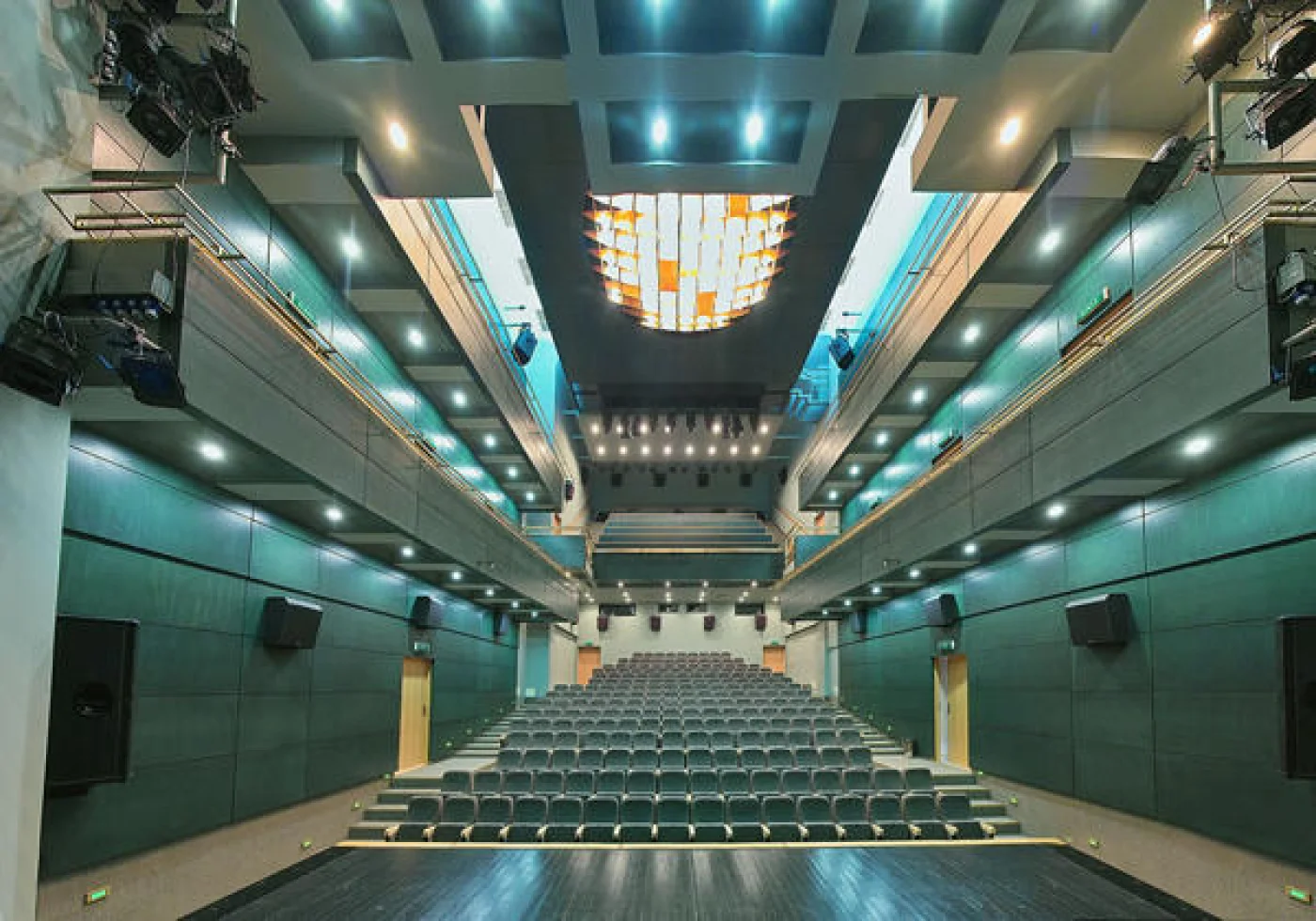 Panoramiczny widok wnętrza dużej sali teatralno-koncertowej z widocznym sceną, rzędami foteli i imponującymi organami koncertowymi.