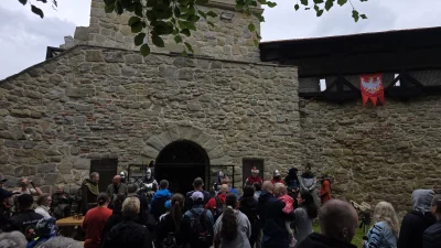 Monumentalna fasada historycznej baszty obronnej, prawdopodobnie części zamku w Nowym Sączu, ukazująca detale architektoniczne i kontekst miejski.