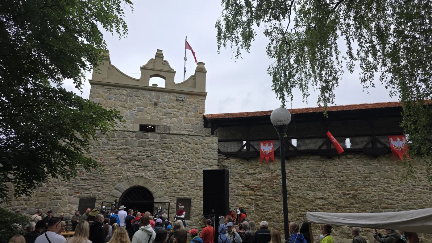 Monumentalna baszta obronna na wzgórzu, częściowo ukryta za drzewami, przedstawiająca historyczny obiekt militarny w Nowym Sączu.