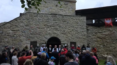 Uroczyste otwarcie Baszty Kowalskiej w Nowym Sączu. Na zdjęciu widoczni są goście i uczestnicy wydarzenia na tle historycznej, kamiennej architektury.